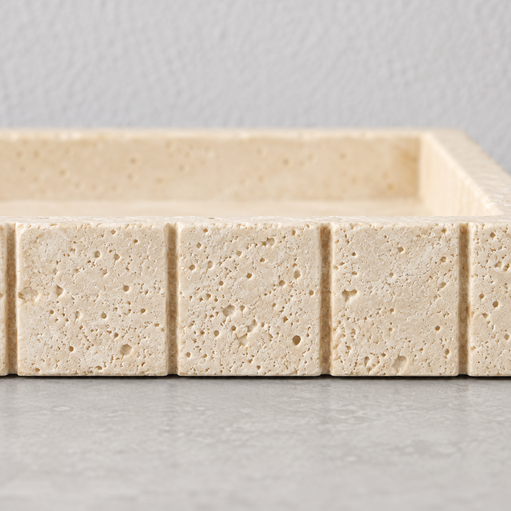 Close up of the carved vertical grooves along the rim of the beige travertine vanity tray.