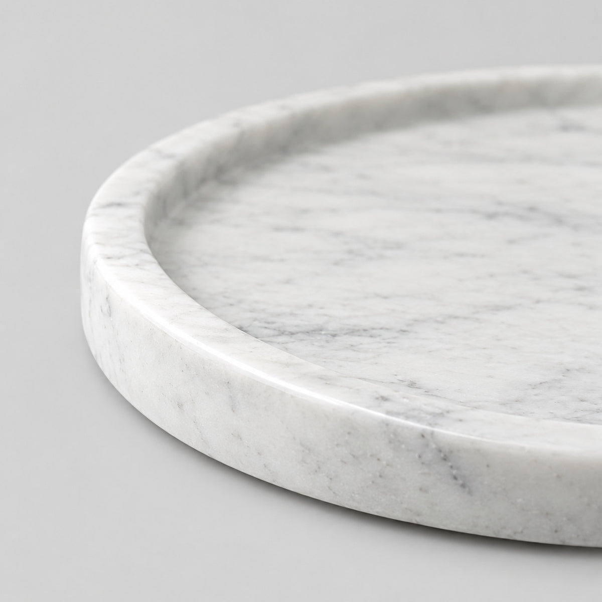 Close up of the smooth raised rim of the round marble tray.