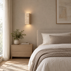 Travertine block wall sconce lit mounted on the plaster wall beside a 150 cm wide double bed against a plain wall