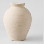 Off-white ribbed ceramic vase on a light gray studio background.