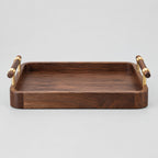 Rectangular walnut serving tray with brass handles in Walnut finish on a light gray studio background.
