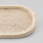 Close up of the smooth rounded rim of the oval travertine tray.