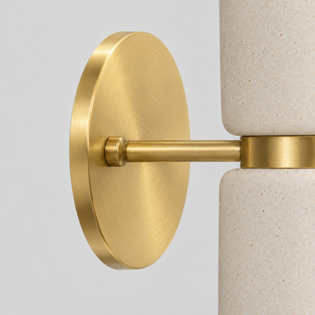 Close up of the round canopy against the wall of the brass dual-light ceramic wall sconce