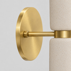 Close up of the round canopy against the wall of the brass dual-light ceramic wall sconce