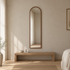 Arched solid wood full-length mirror in Walnut finish mounted on a greige plaster wall above a 120 cm wide low bench in a calm room.