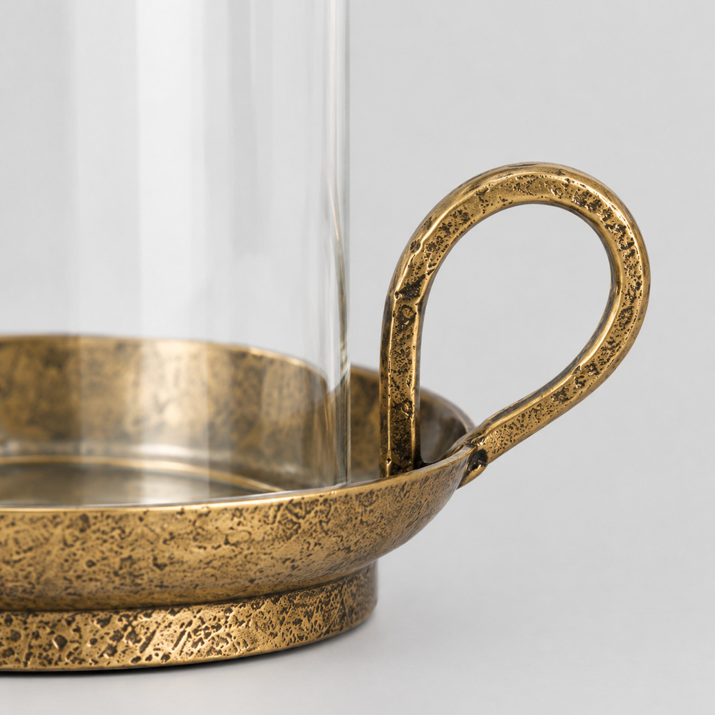 Close up of the curved loop handle on the brass base of the hurricane candle holder.