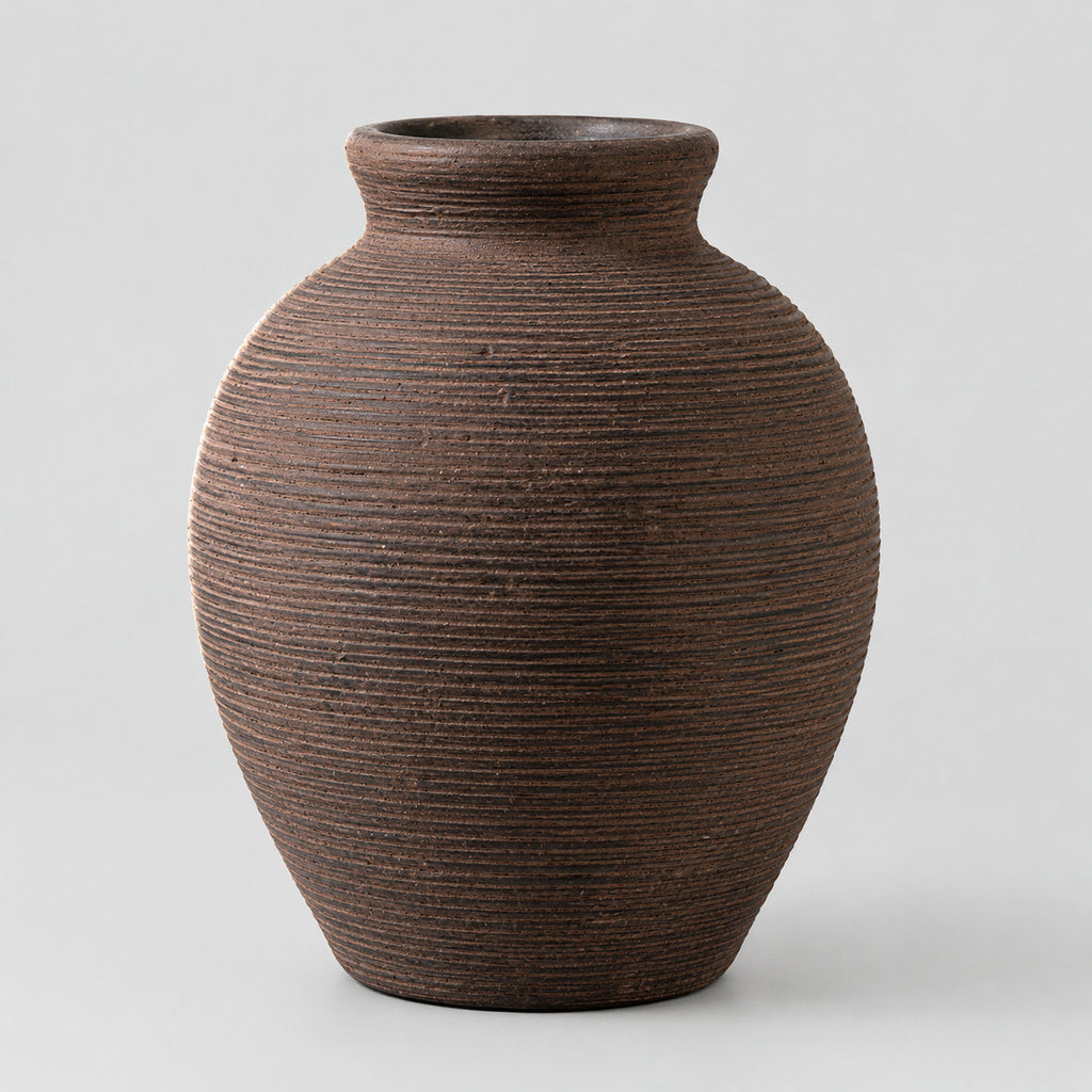 Vintage brown ribbed ceramic vase on a light gray studio background.
