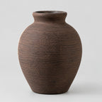 Vintage brown ribbed ceramic vase on a light gray studio background.