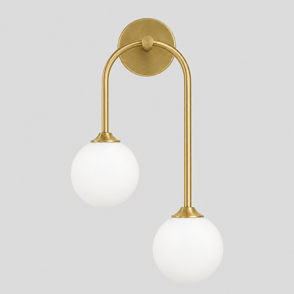 Brass asymmetric double-globe arch wall sconce switched off on a light gray studio background.