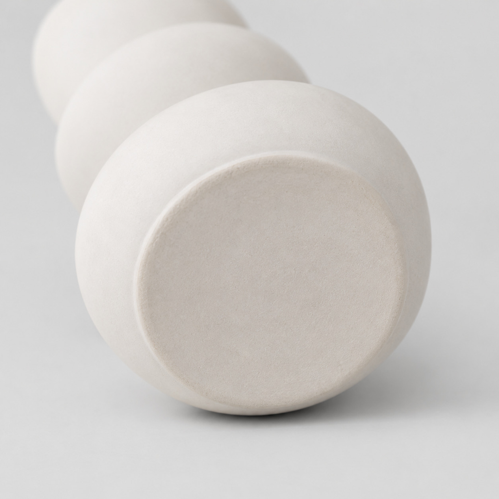 Close up of the flat circular base of the white stacked pebble ceramic vase.