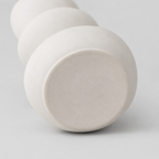 Close up of the flat circular base of the white stacked pebble ceramic vase.