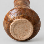 Close up of the unglazed circular foot of the coarse pottery bud vase.