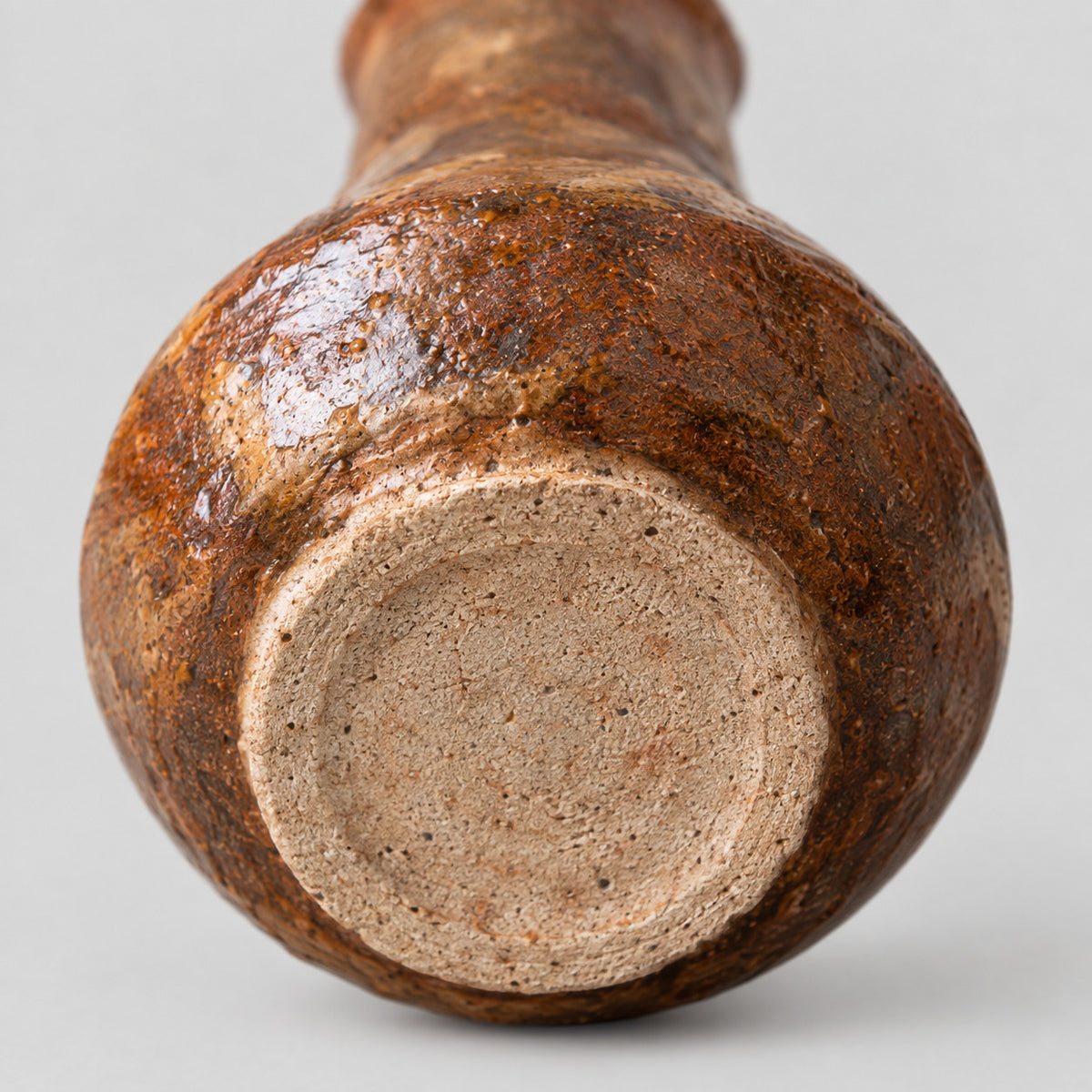 Close up of the unglazed circular foot of the coarse pottery bud vase.