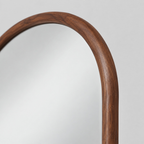 Close up of the curved frame corner along the arched top edge of the arched solid wood full-length mirror.