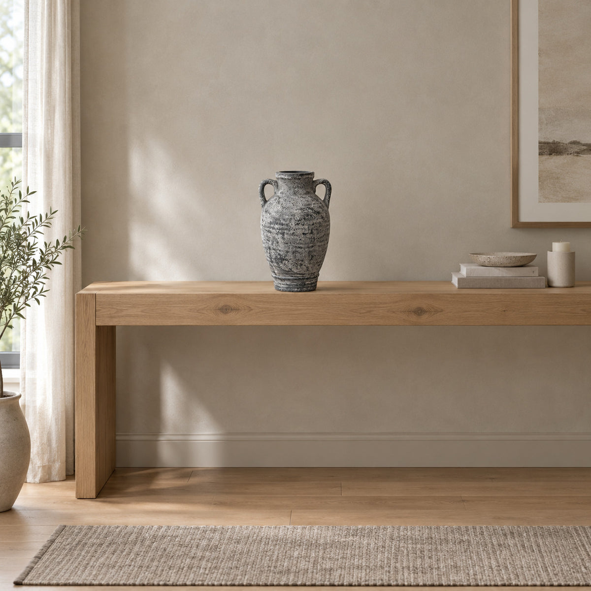 Weathered gray ceramic amphora vase on an oak console table in a calm room