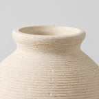 Close up of the smooth rounded rim at the opening of the off-white ceramic vase.