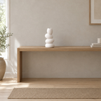 White stacked pebble ceramic vase on an oak console table in a calm room.