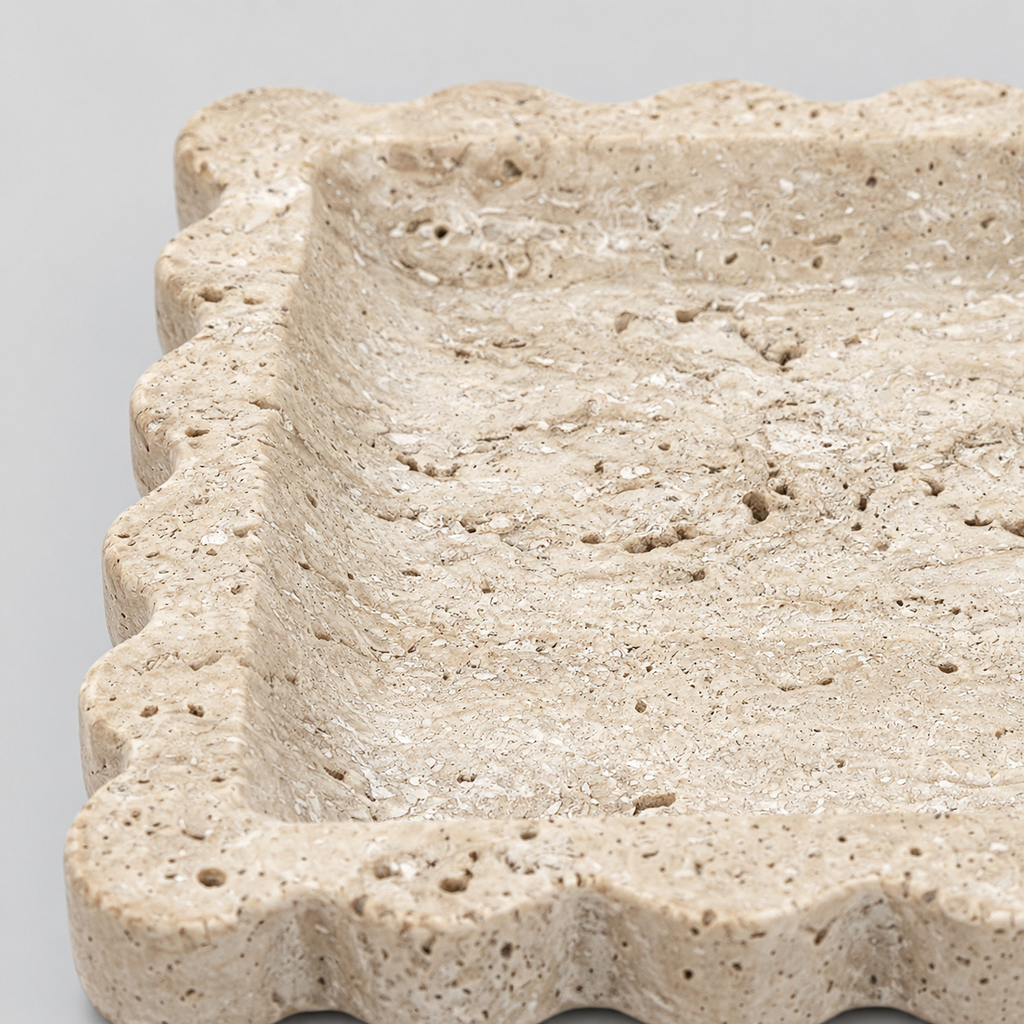 Close up of the porous surface texture of the travertine of the scalloped square stone tray in Yellow Travertine.