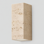 Travertine block wall sconce in travertine on a light gray studio background