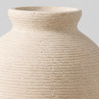 Close up of the carved horizontal ribbed pattern across the body of the off-white ceramic vase.