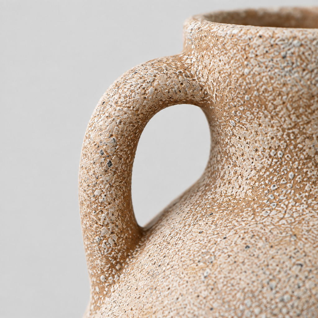 Close up of the curved ceramic loop handle where it connects to the flared neck of the ceramic amphora vase.