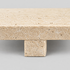 Close up of the rectangular slab foot beneath the beige travertine tray