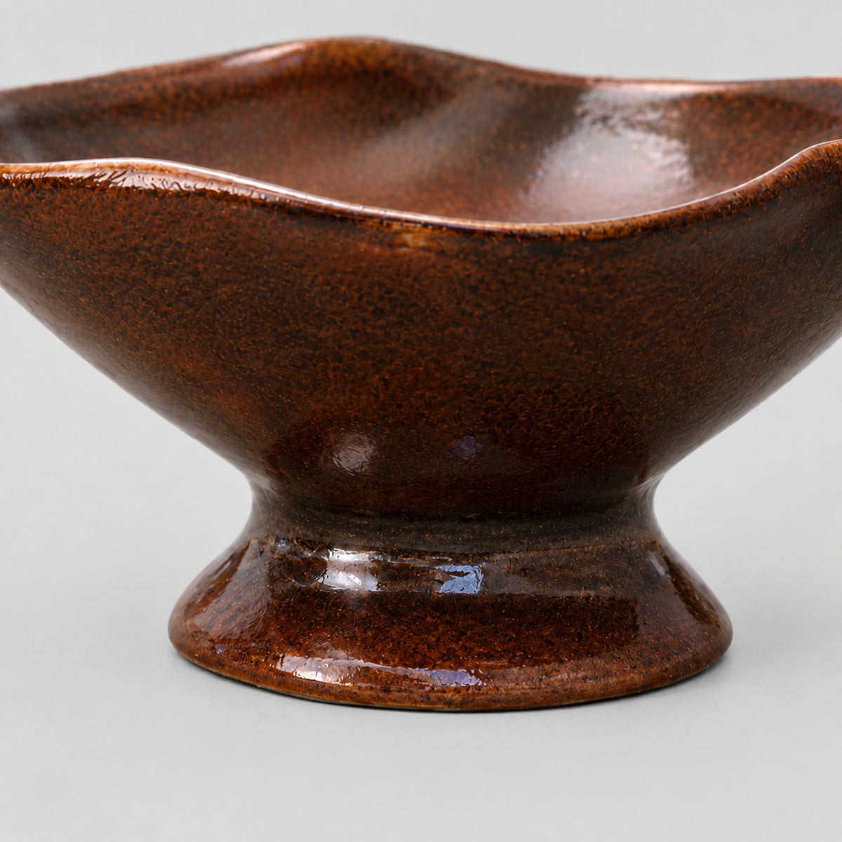 Close up of the flared pedestal base of the ceramic footed planter bowl in Glazed Brown.