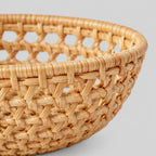 Close up of the openwork lattice weave of the flared sides of the woven rattan round basket tray