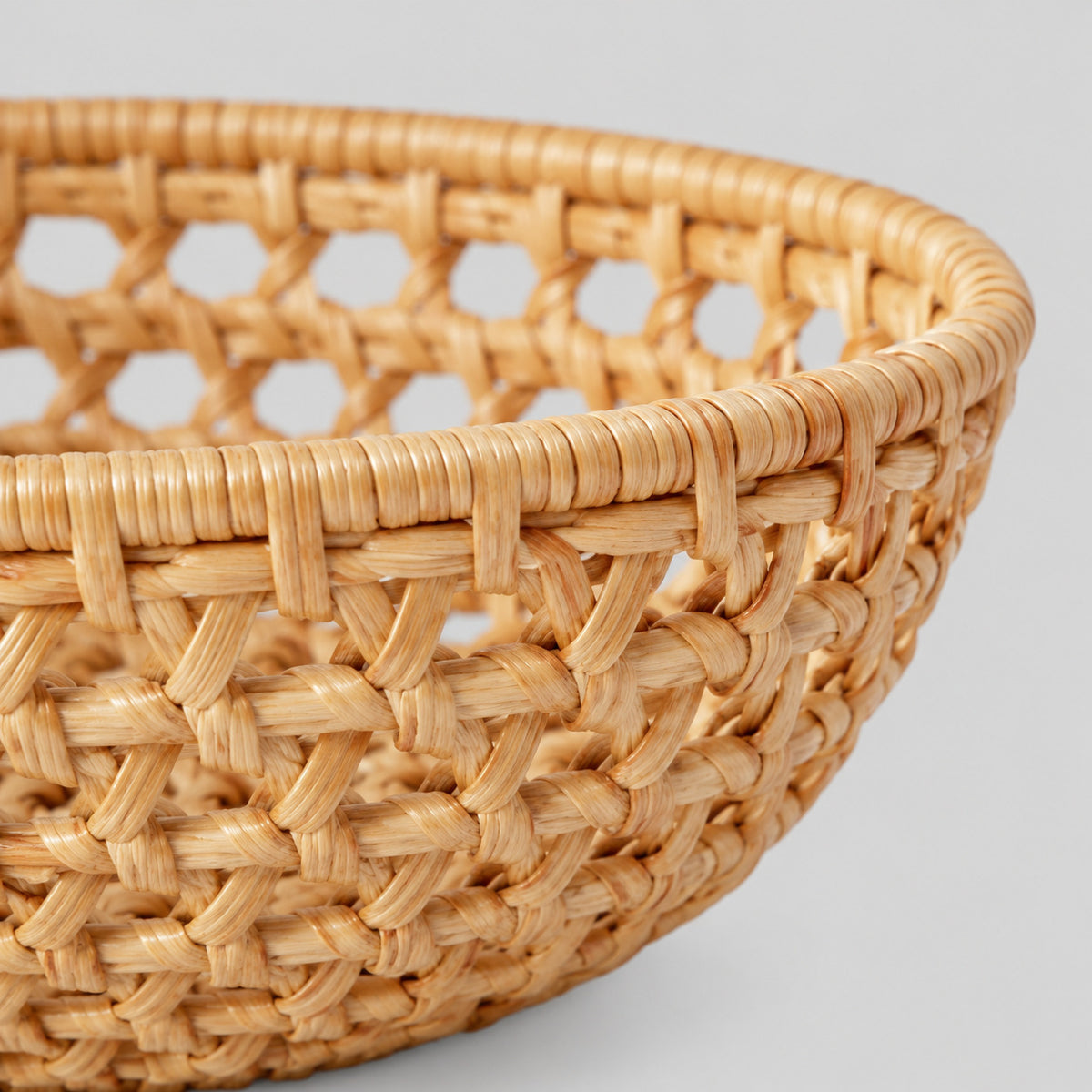 Close up of the openwork lattice weave of the flared sides of the woven rattan round basket tray