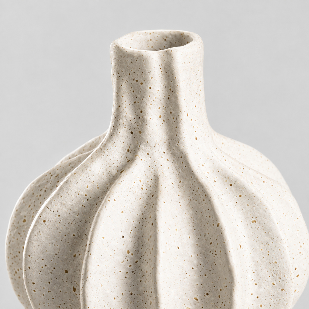 Close up of the speckled matte glaze across the fluted ridges of the short fluted ceramic vase.
