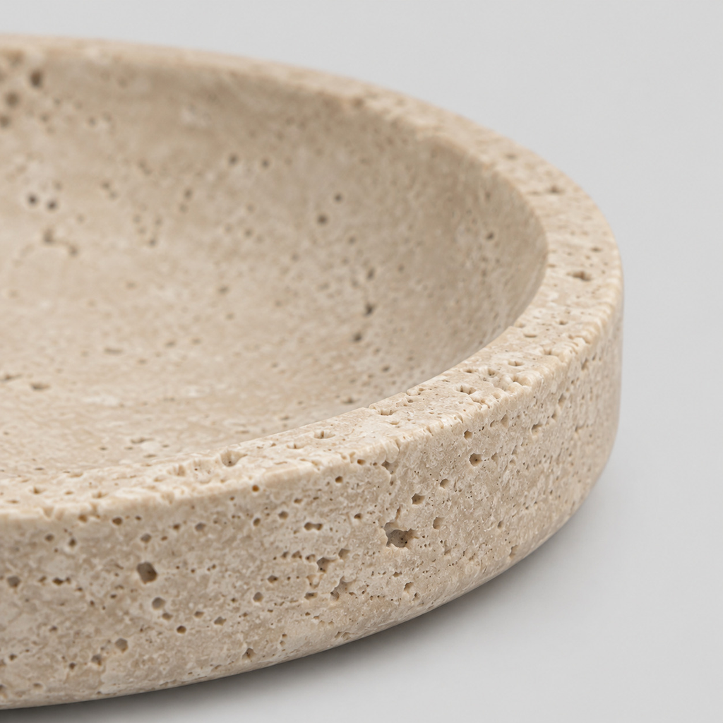 Close up of the smooth rounded rim of the round beige travertine dish