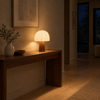 Walnut mushroom table lamp lit in the evening on a walnut console table in a hallway, the only light in the room