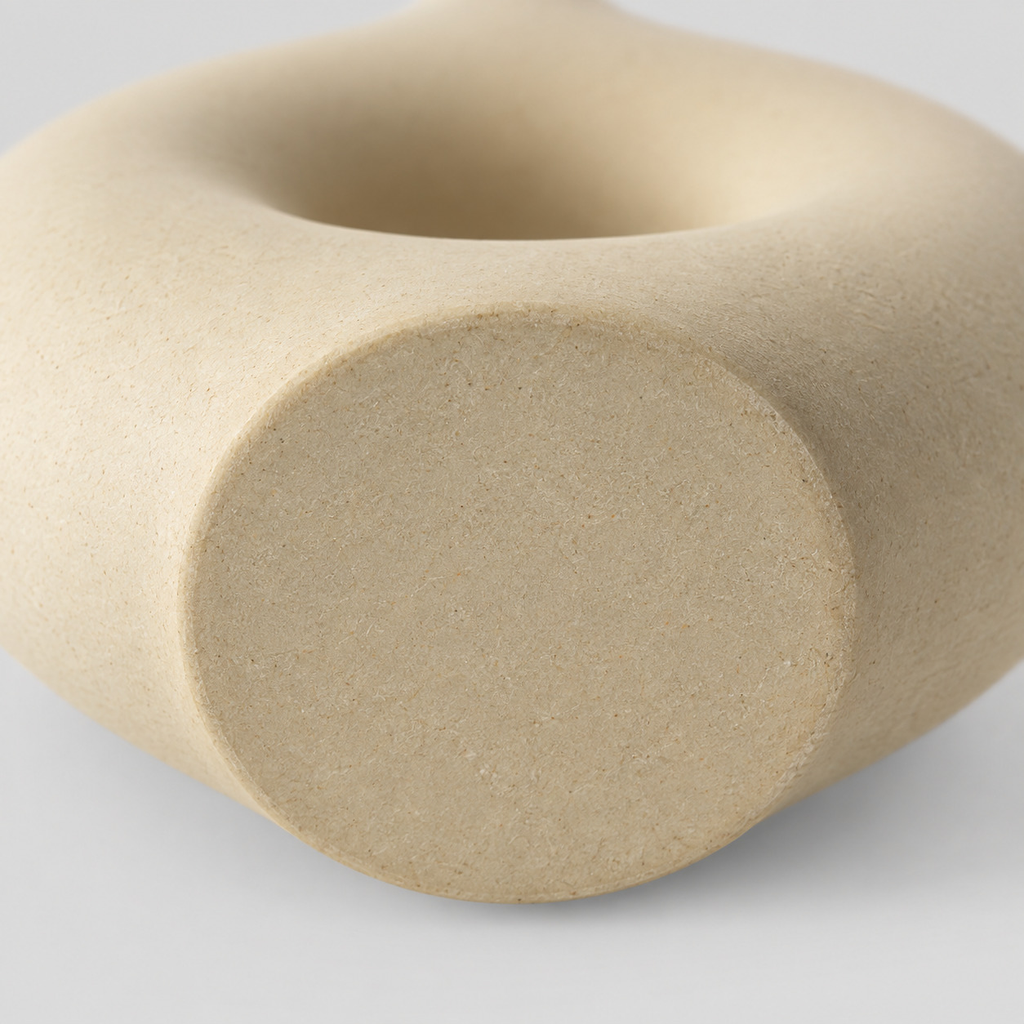 Close up of the flat circular base of the beige hollow round ceramic vase.