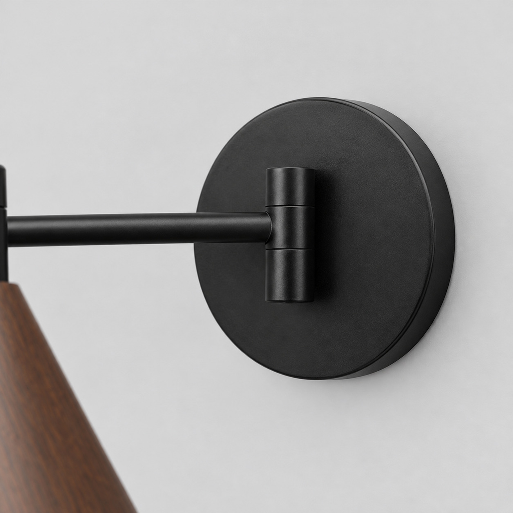 Close up of the round canopy against the wall of the walnut swing-arm wall sconce.
