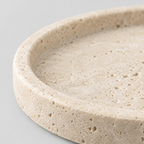 Close up of the pitted surface texture of the round beige travertine catchall tray.