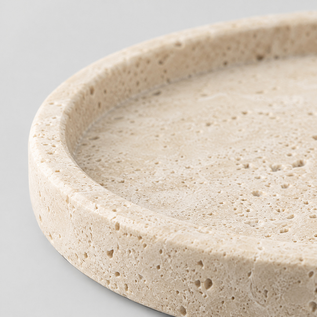 Close up of the pitted surface texture of the round beige travertine catchall tray.