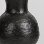 Close up of the dimpled surface texture of the rounded body of the black ceramic vase.