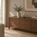 Cream crinkled ceramic vase on a 160 cm wide walnut sideboard beneath a framed print with a bunch of eucalyptus in the vase.