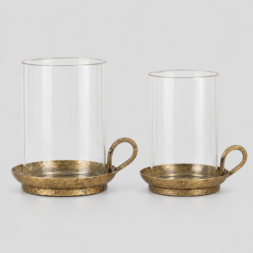 Set of two brass hurricane candle holders in Antique Brass on a light gray studio background.