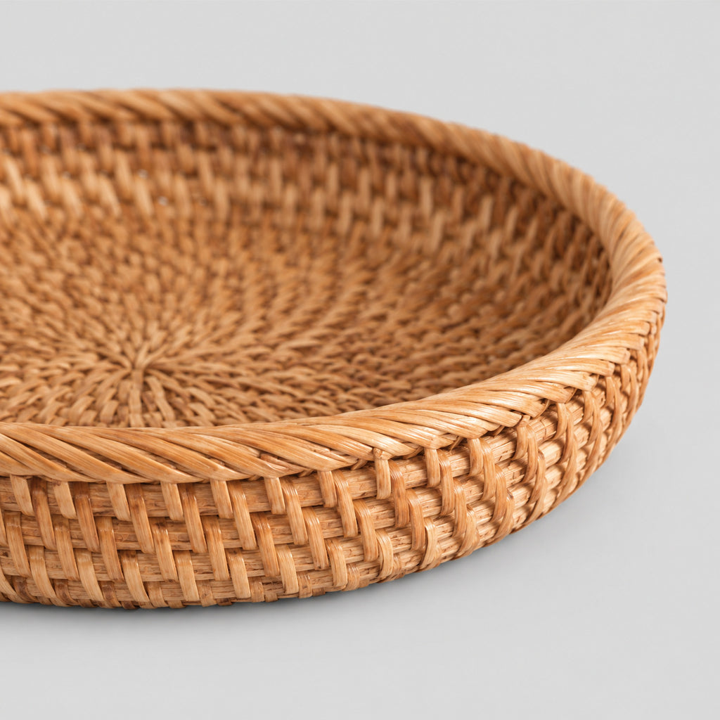 Close up of the coiled rim of the shallow round woven rattan basket tray in Natural Rattan.