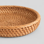 Close up of the coiled rim of the shallow round woven rattan basket tray in Natural Rattan.