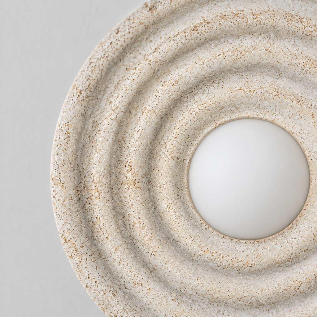 Close up of the rim where the glass shade meets the brass fitter of the Distressed White circular concentric ripple wall sconce.