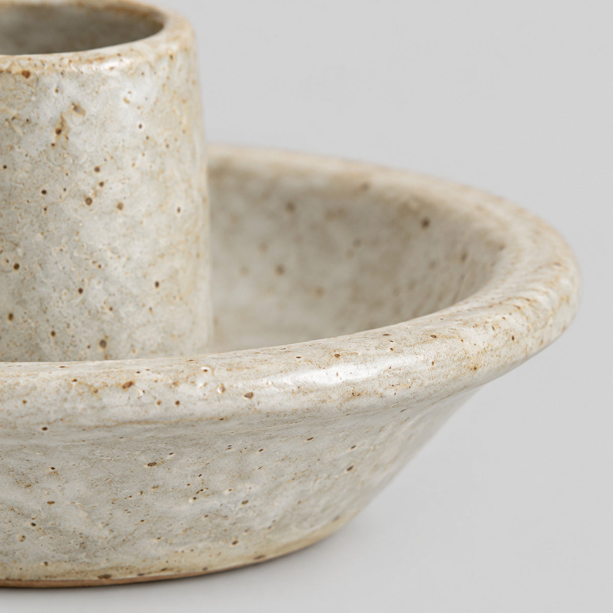 Close up of the speckled glaze texture on the saucer rim of the Speckled Off-White ceramic taper candle holder
