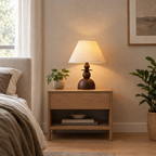 Walnut table lamp lit standing on a 48 cm wide oak bedside table against a plain wall.