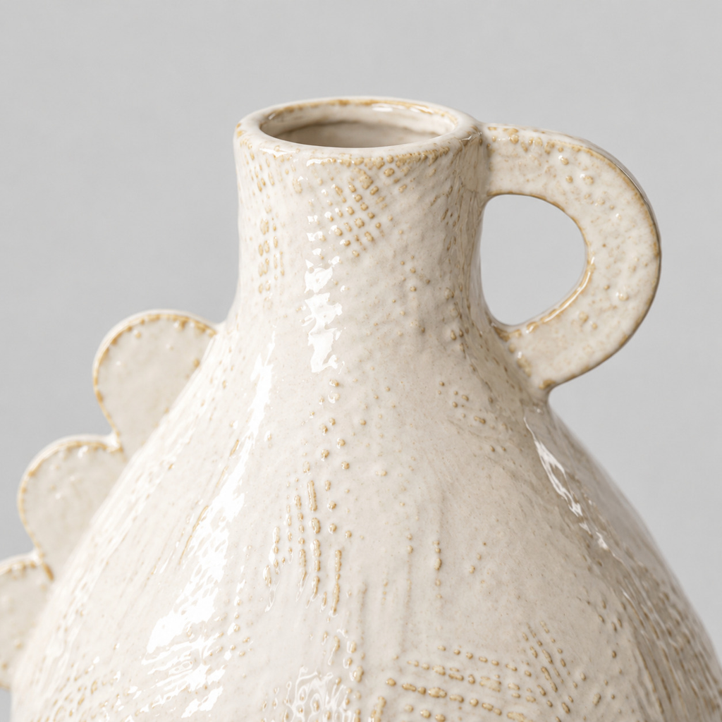 Close up of the curved loop handle at the neck of the off-white scalloped ceramic vase
