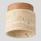 Cylindrical travertine flush mount ceiling light in natural wood finish on a light gray studio background.