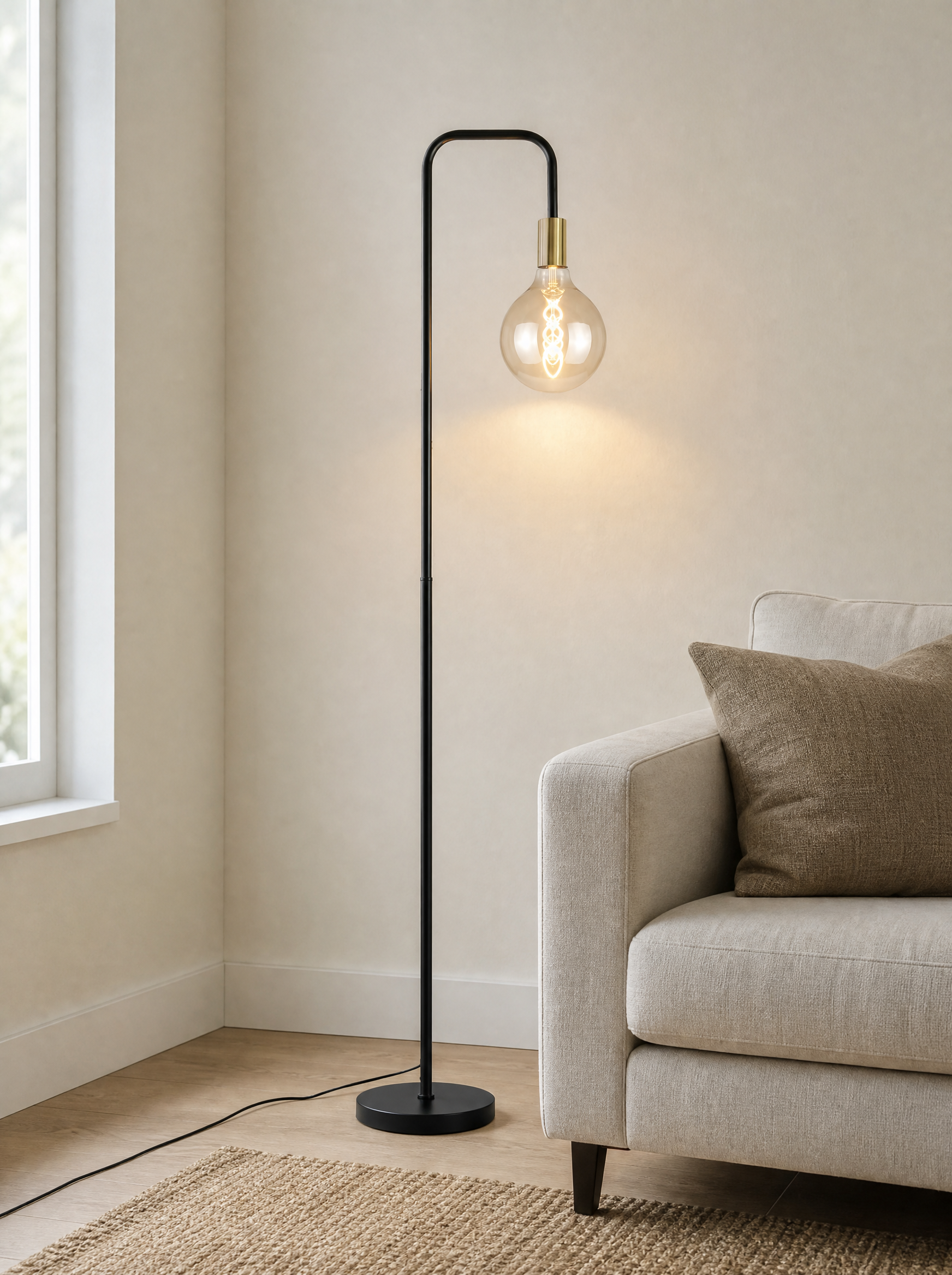 Brass socket floor lamp lit beside a sofa against a plain wall