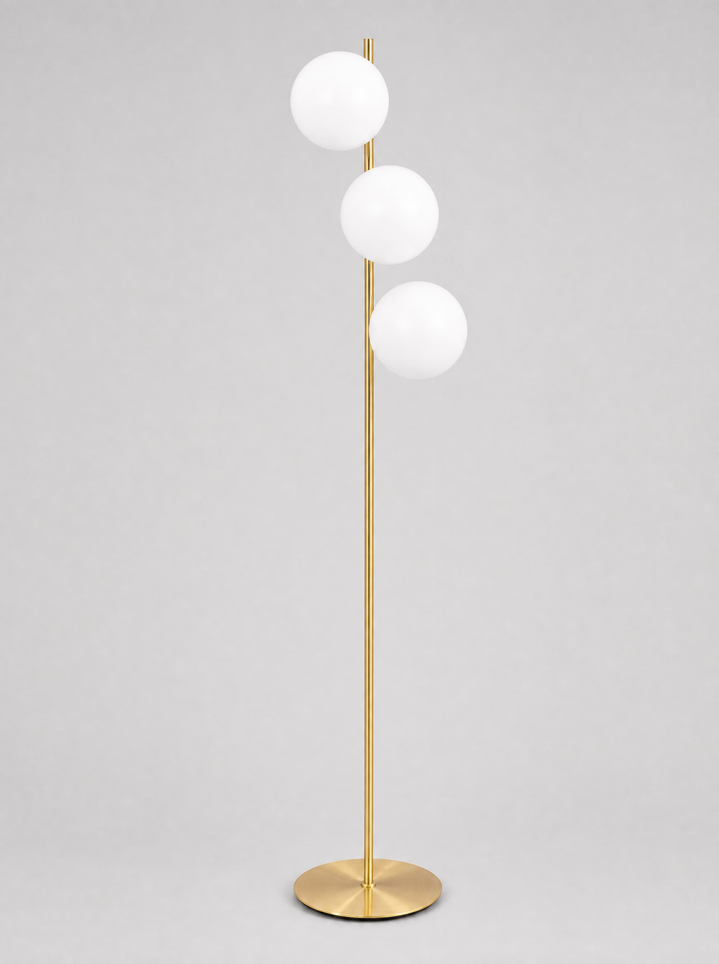 Brass floor lamp with three opal glass globes on a light gray studio background