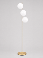Brass floor lamp with three opal glass globes on a light gray studio background