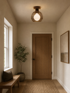 Coiled metal flush ceiling light lit on the ceiling of an entrance hall
